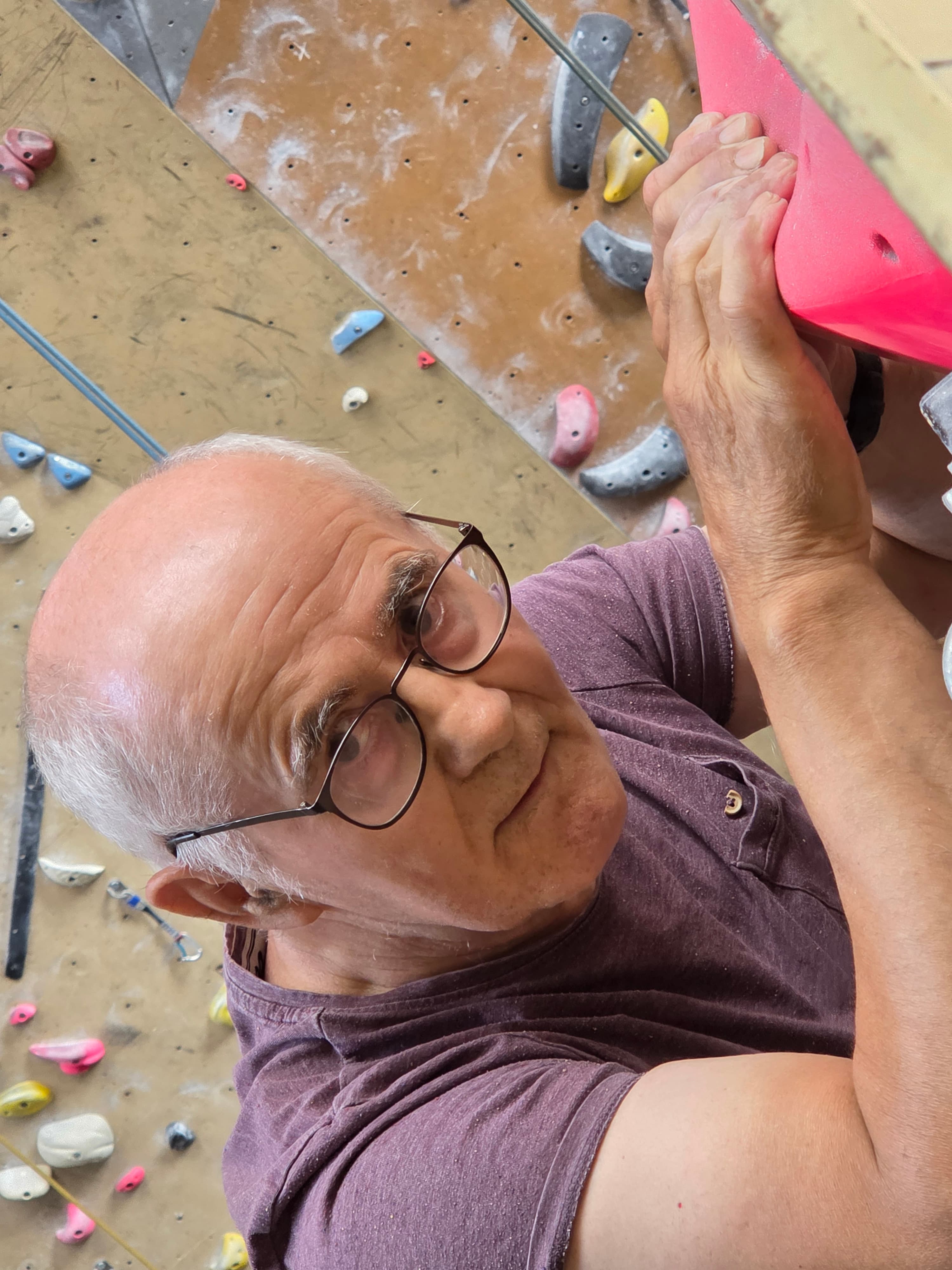 Deelnemer kijkt lachend omlaag vanaf de wand